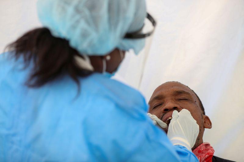 A medical worker wearing personal protective equipment (PPE) takes a swab sample from a man, as South Africa starts to relax some aspects of a stringent nationwide coronavirus disease (COVID-19) lockdown in Diepsloot near Johannesburg, South Africa, May 8, 2020. REUTERS/Siphiwe Sibeko
